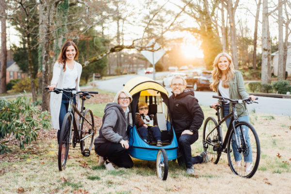 Two women with bicycles stand on either side of a man, woman and child with a stroller