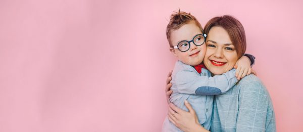 A woman hugs a child in glasses